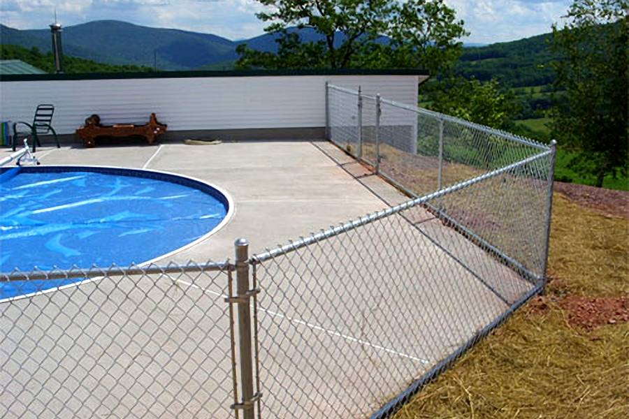 Chain link fence is used as swimming pool safety enclosure for in ground pool.