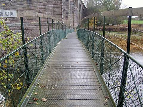 A sidewalk with green chain link railing.