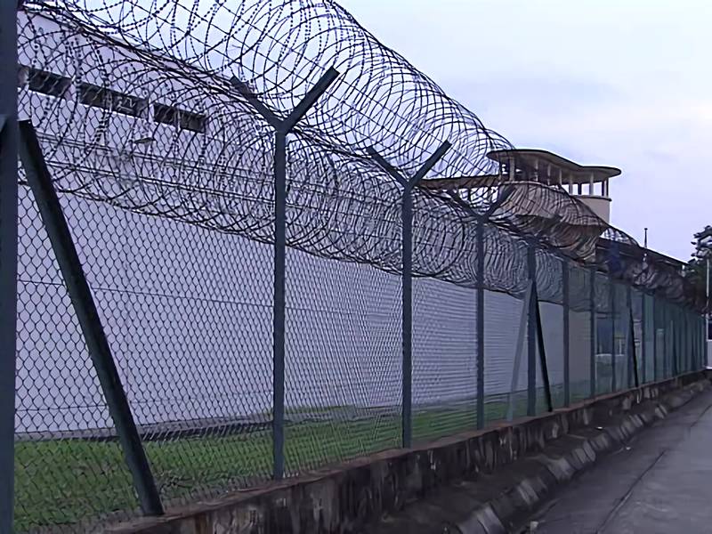 Загородка звена цепи использована как загородка тюрьмы окружающая здание.