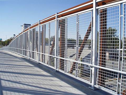 A footbridge protection railing is made of steel grating.