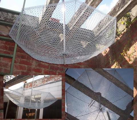 A umbrella is composed of ring mesh, upside down on wood pillar.