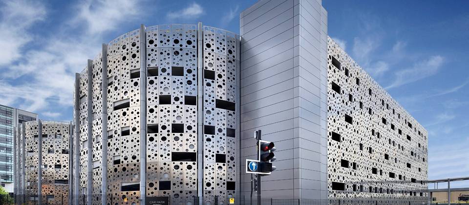 Building wall made of perforated metal with different sizes of round holes.