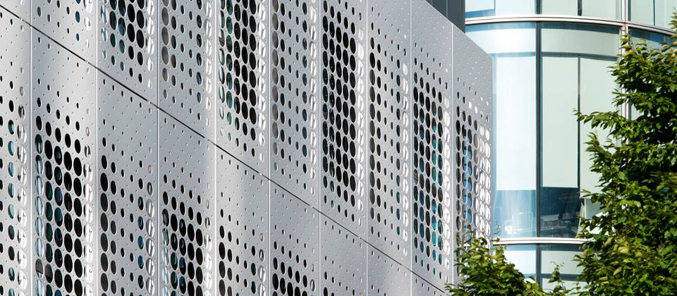 Perforated metal building facade are both beautiful and shade.
