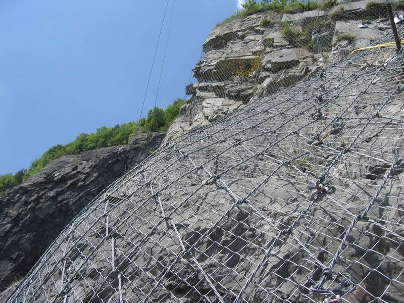 Spider spiral rope mesh with chain link mesh as an active rockfall barrier system.