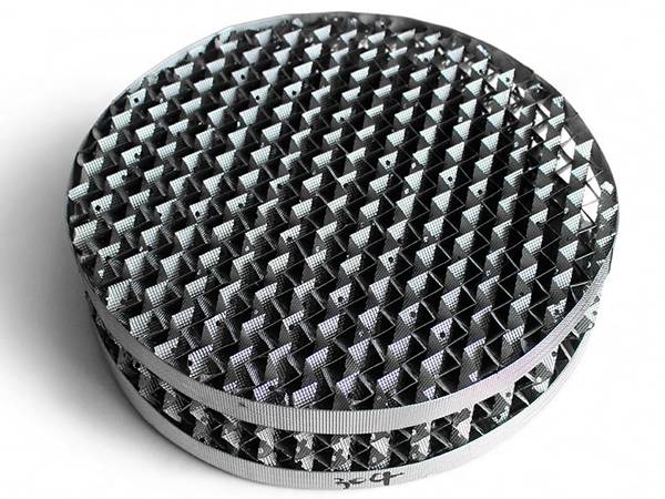 A piece of stainless steel perforated plate structured packing on the gray background.