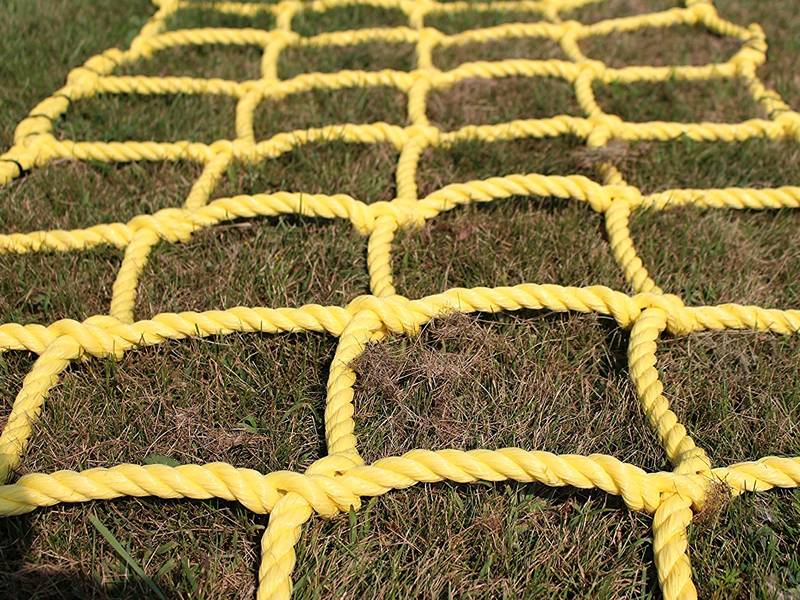 A piece of yellow climbing net were placed on the grass.